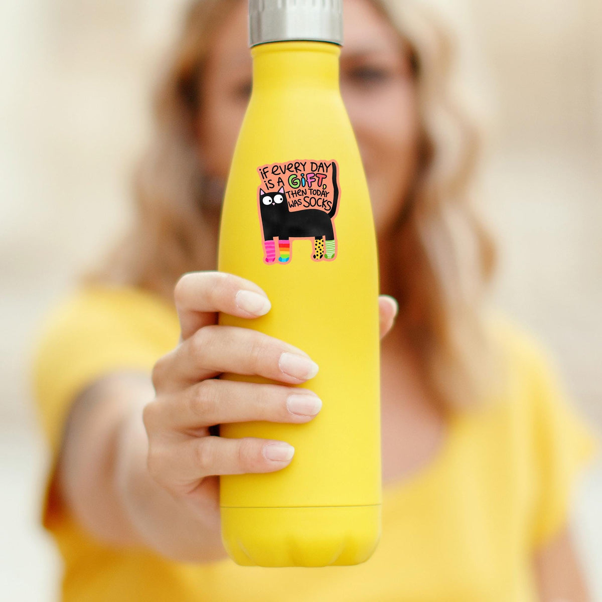 Black cat socks sticker on a yellow water bottle held in hand