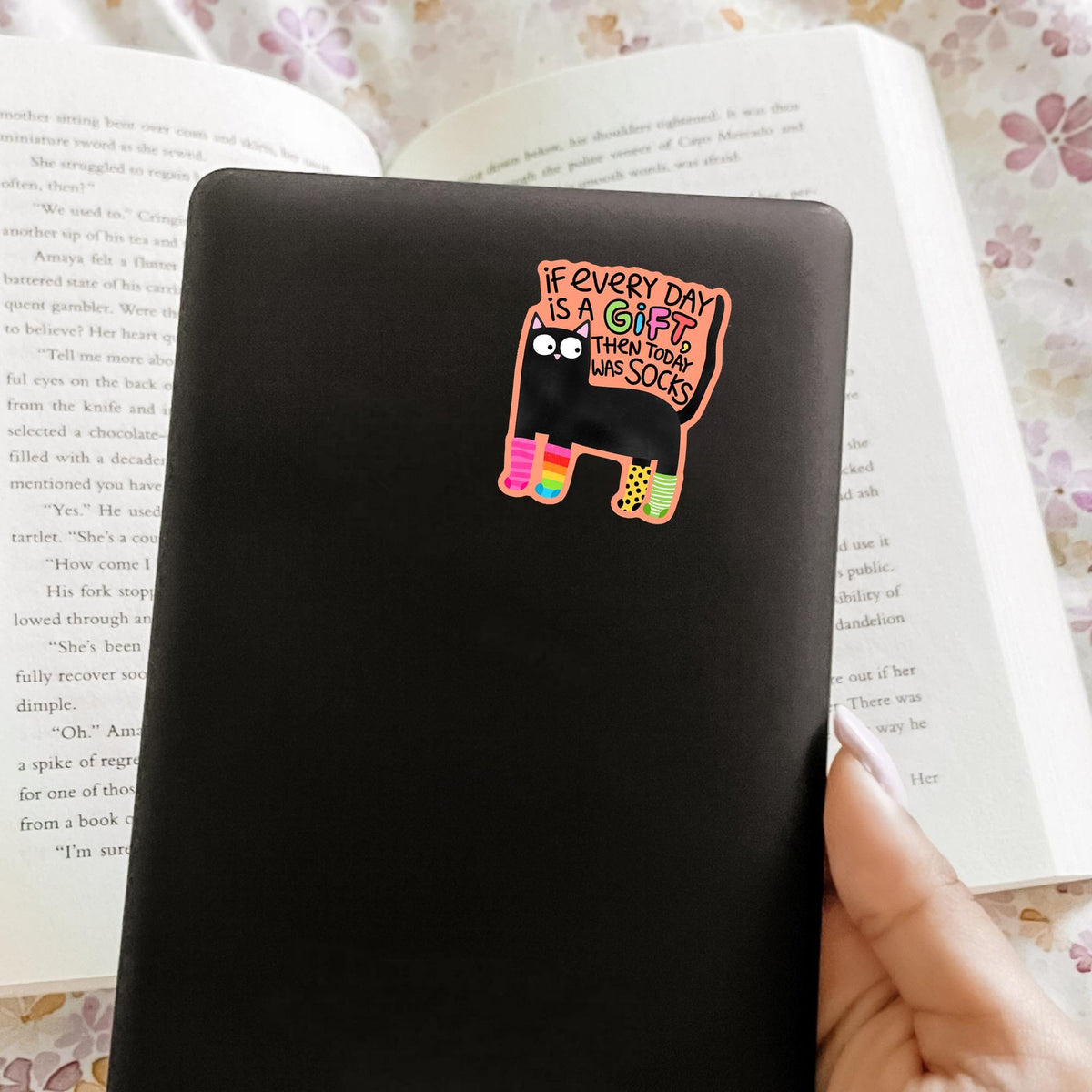 Black cat socks sticker on a black notebook
