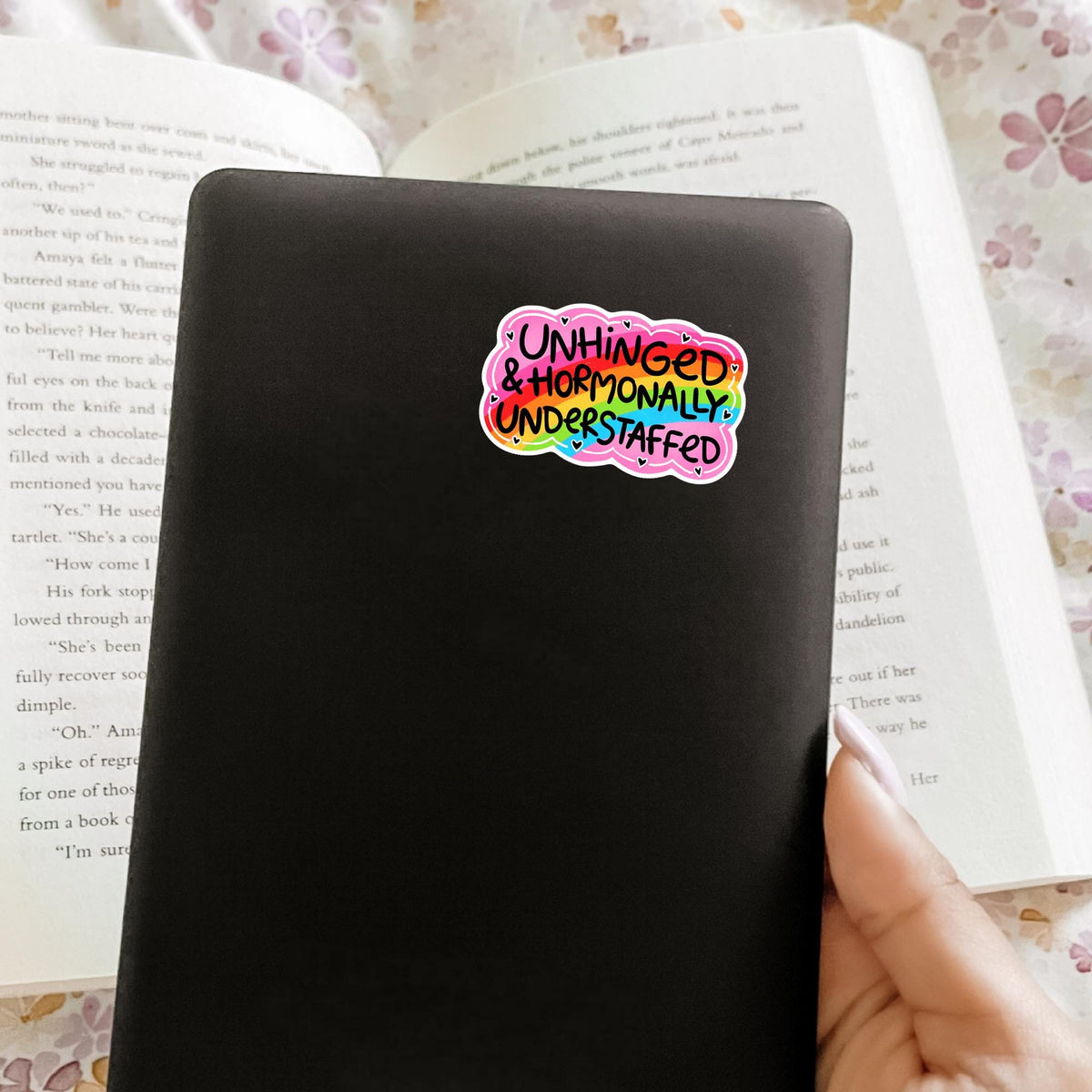 Unhinged and Understaffed sticker on a black notebook cover, matte vinyl snarky quote decal, relatable gift idea for journaling and desk decor
