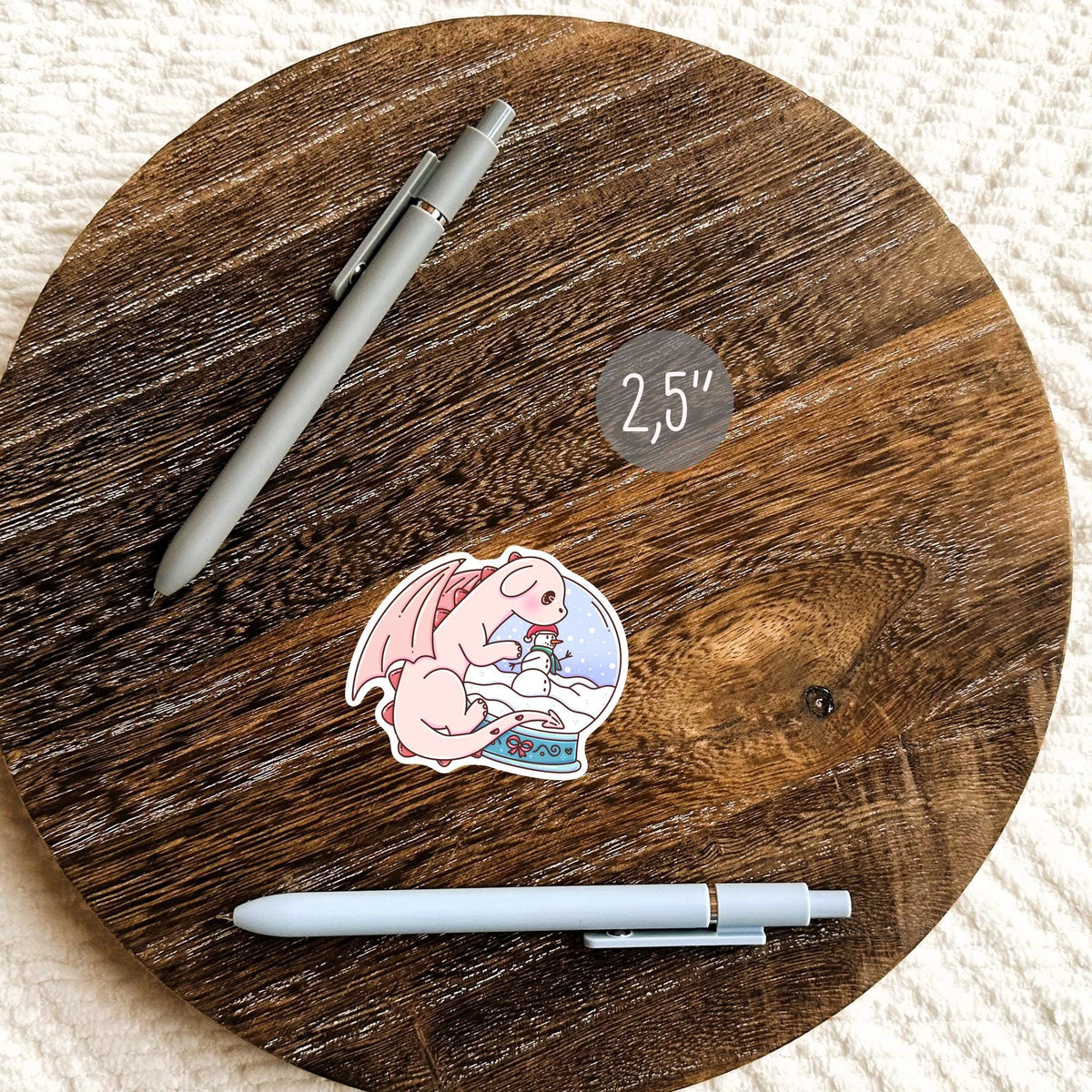 Snow Globe Dragon sticker next to pens on a round wooden board, aesthetic planner and journal sticker, waterproof vinyl cozy winter gift