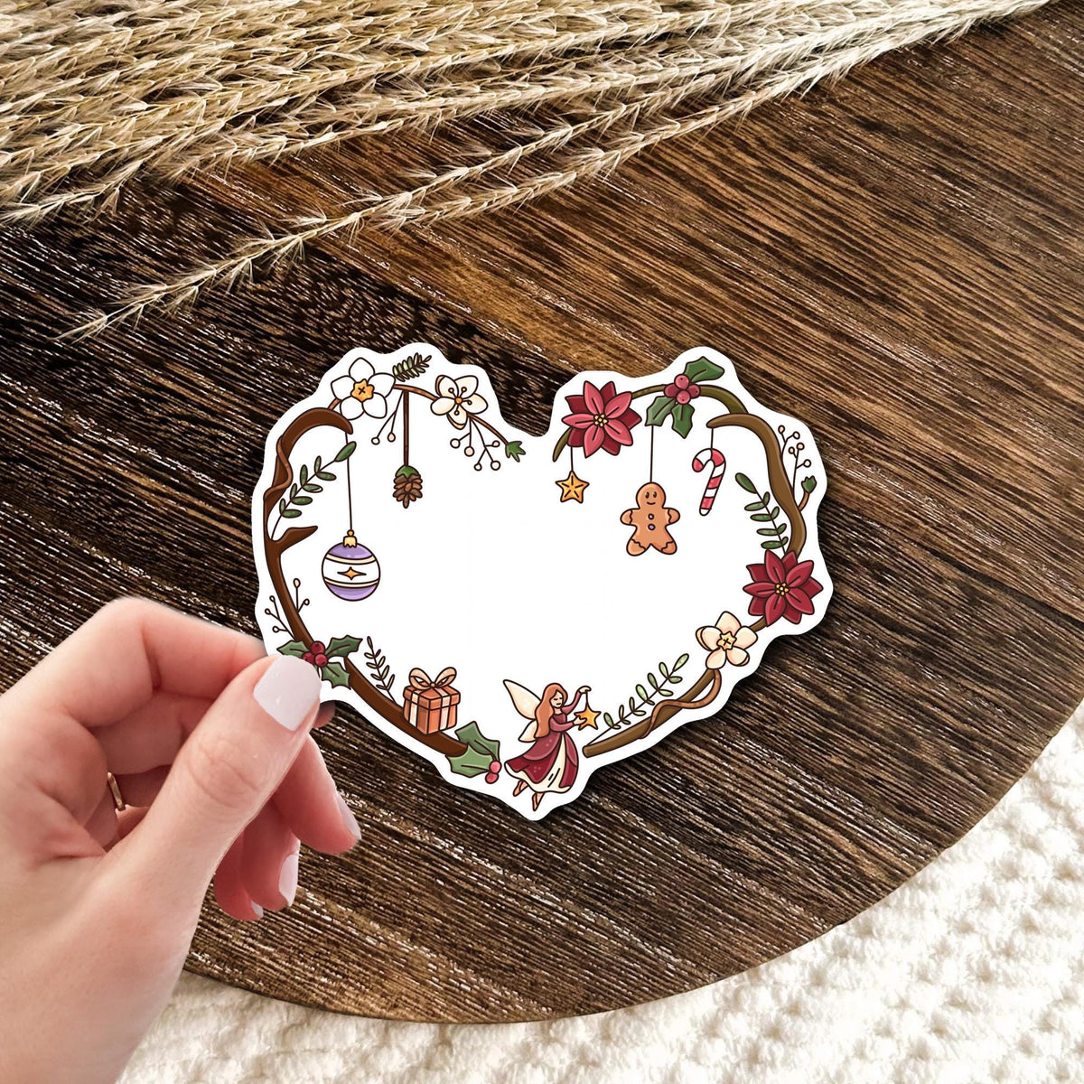 Christmas Fairy Heart waterproof vinyl die-cut sticker held in hand, cute holiday wreath sticker with ornaments and red flowers, festive gift idea