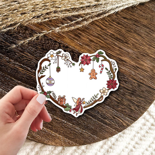 Christmas Fairy Heart waterproof vinyl die-cut sticker held in hand, cute holiday wreath sticker with ornaments and red flowers, festive gift idea