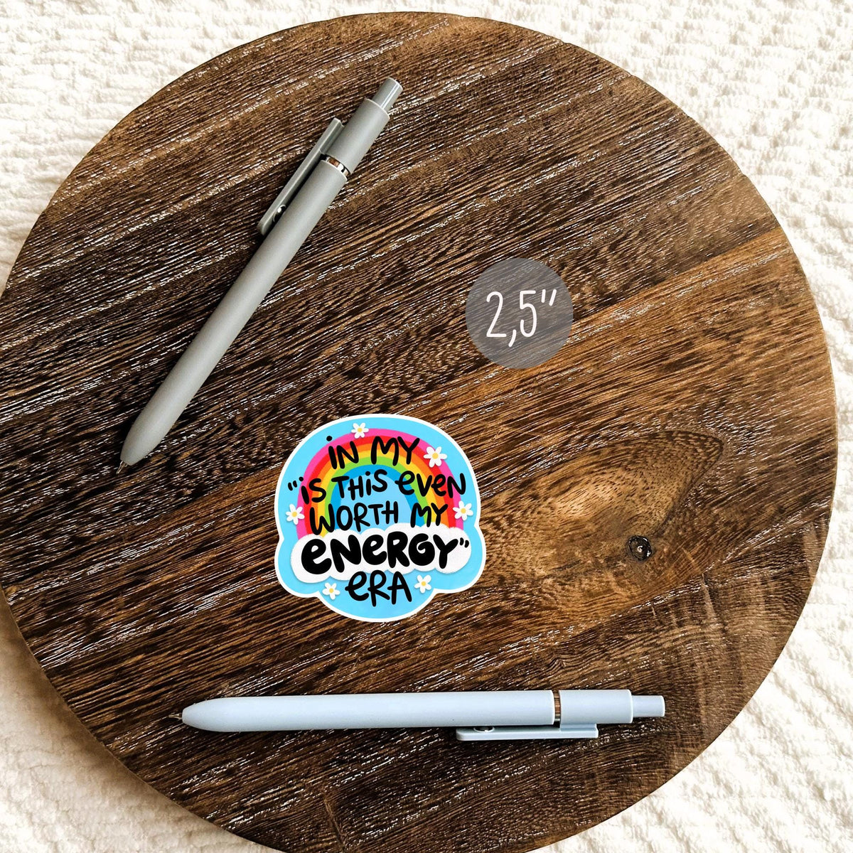 Funny Energy Era sticker beside a pen on a round wooden surface, waterproof snarky quote decal gift for notebook and planner fans