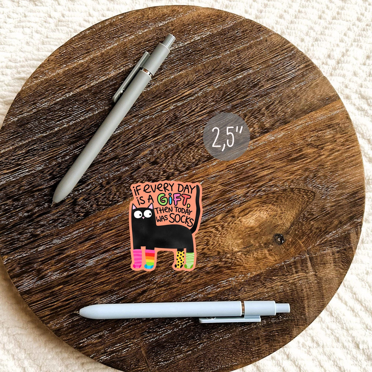 Black cat socks sticker on a round wood board with a pen
