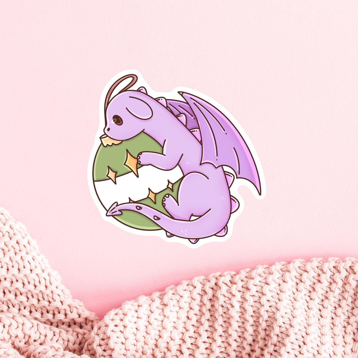 Ornament Dragon die-cut vinyl sticker on a soft pink background, cute waterproof Christmas fantasy decal in matte, glitter and holographic finish